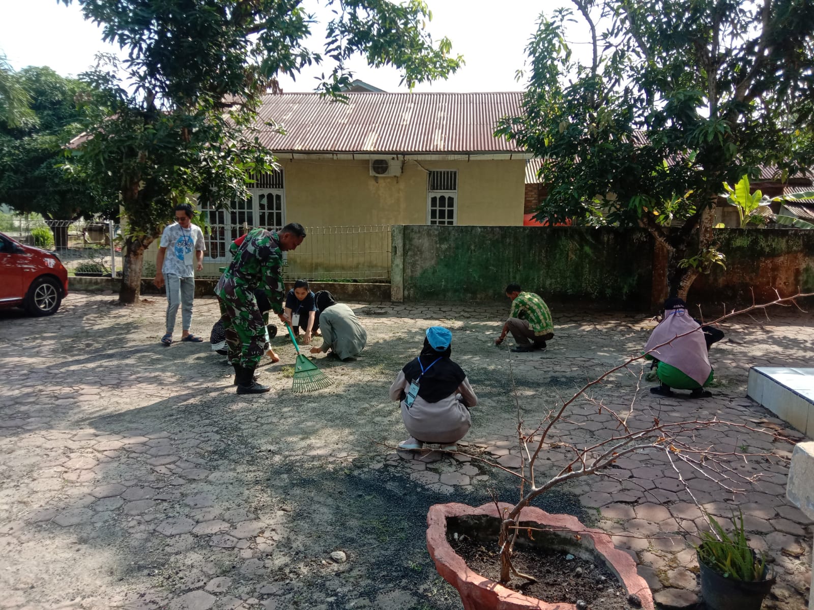 Sertu Ramli dan Mahasiswa KKN Gotong Royong di Halaman Kantor Lurah
